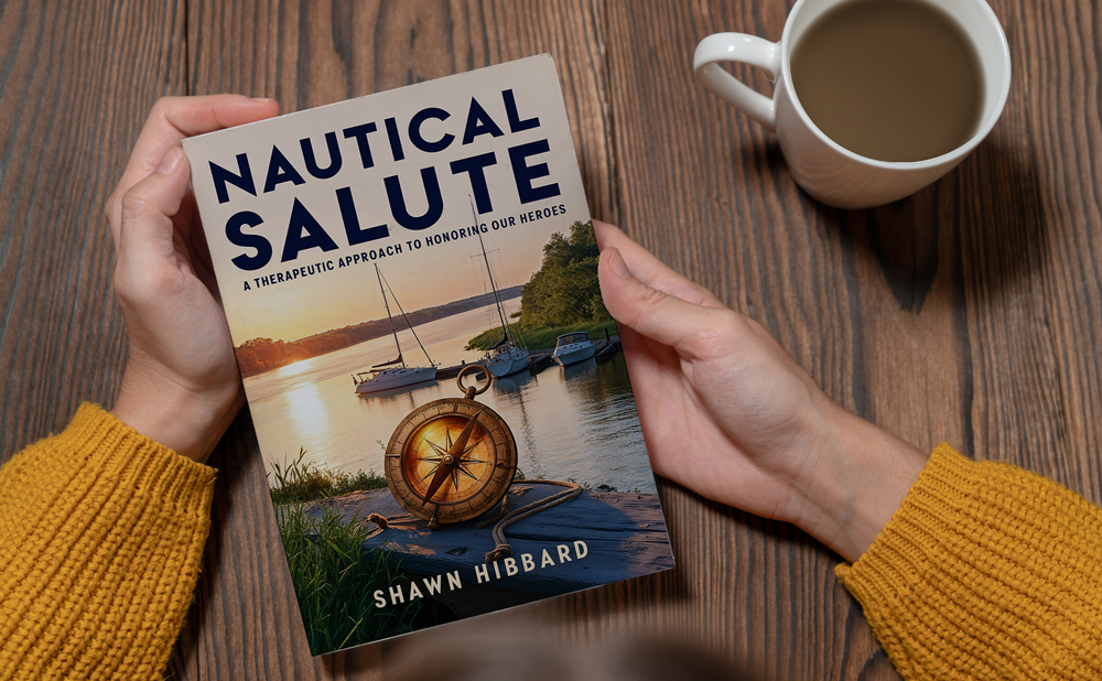 Hands holding the Nautical Salute paperback beside a coffee cup