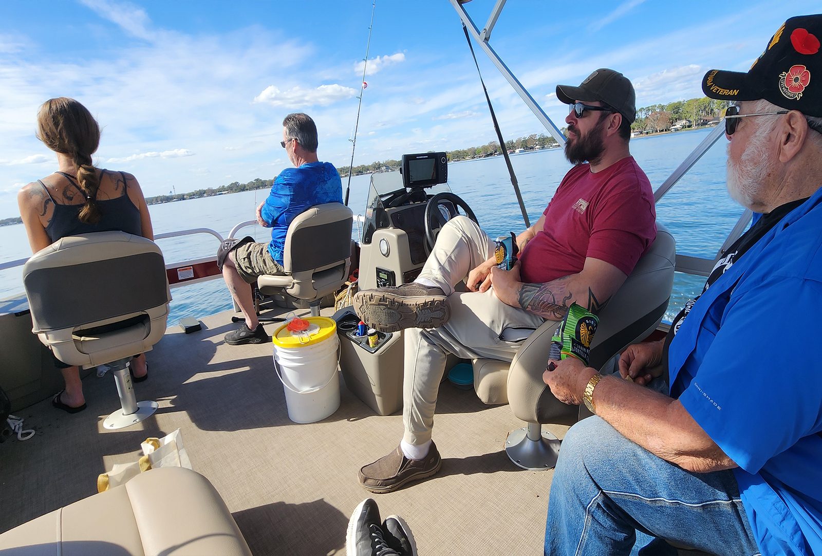 Group of veterans fishing from a pontoon boat under a blue sky