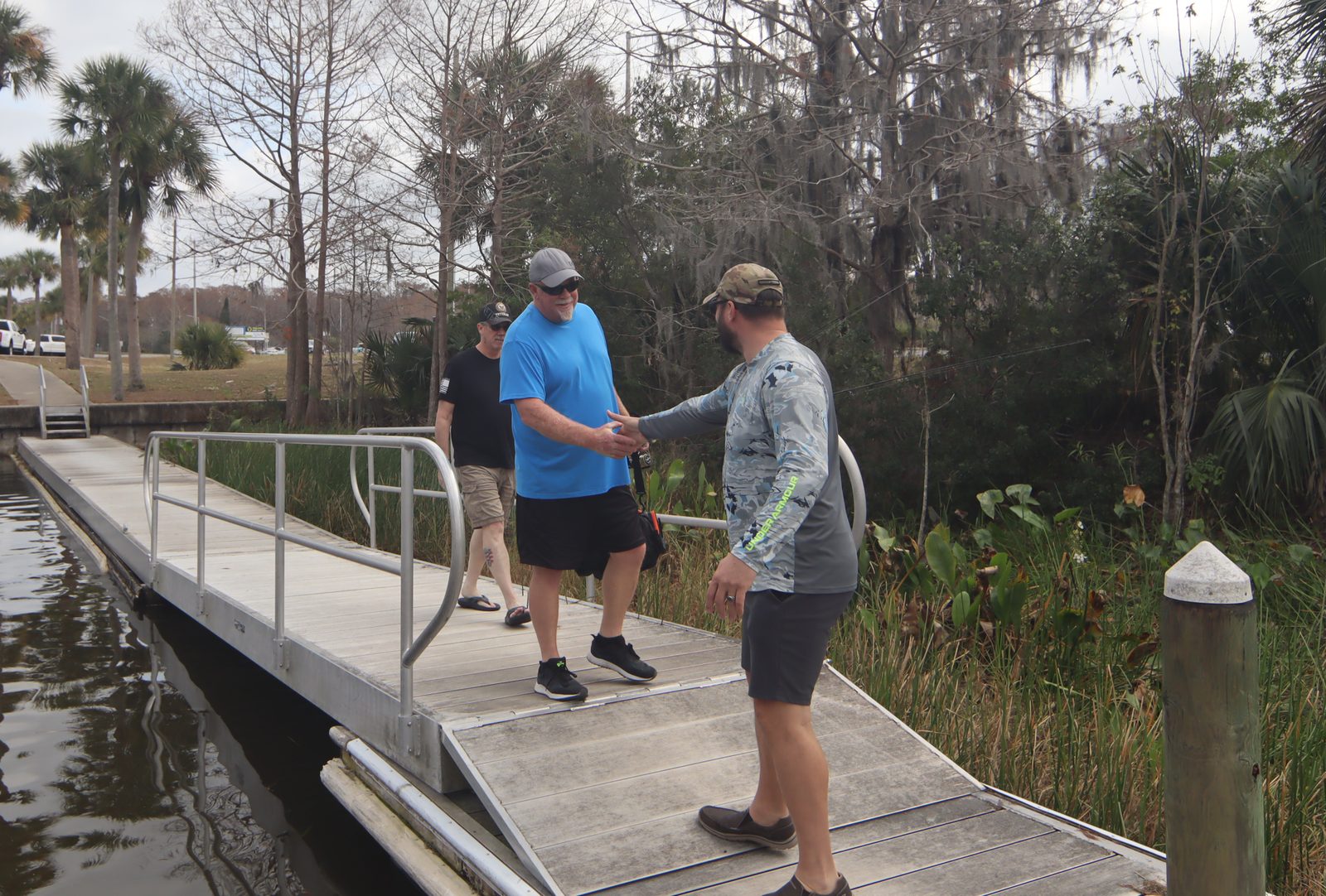 Group of veterans greeting each other on a dock beside a boat on the lake