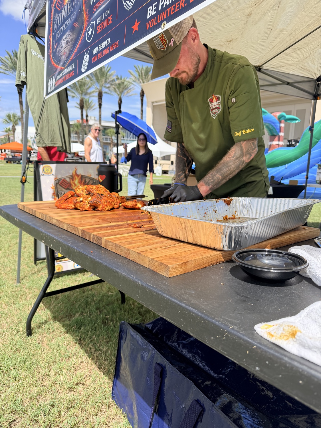 Carving smoked chicken at an outdoor Kombat Kitchen event